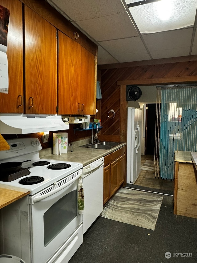 kitchen featuring wood walls, a paneled ceiling, white appliances, and sink