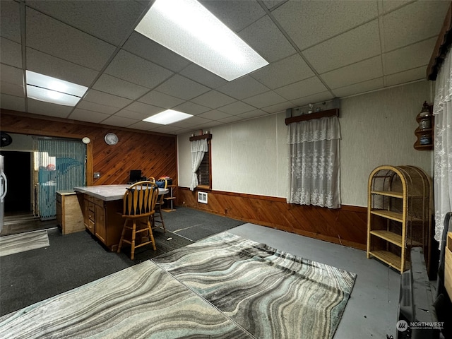 bedroom featuring wooden walls and a drop ceiling