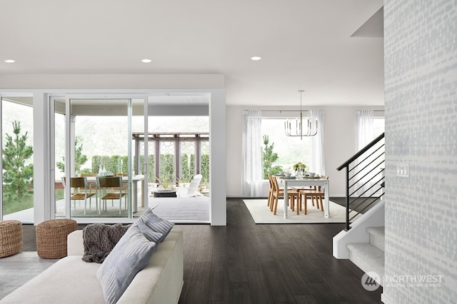 living room featuring dark wood-type flooring, a notable chandelier, and a healthy amount of sunlight