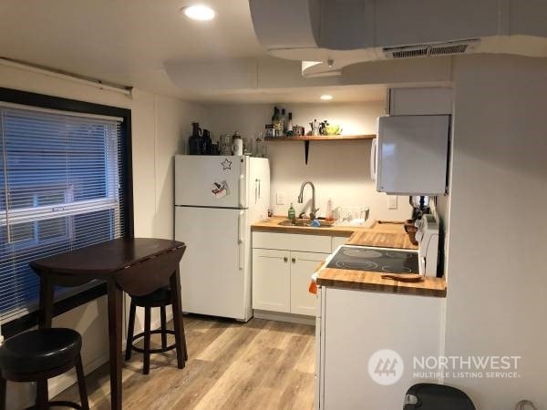 2142 Alki Ave SW Unit 1-5, Seattle, WA 98116 - kitchen with light hardwood / wood-style floors, white refrigerator, white cabinets, sink, and butcher block countertops