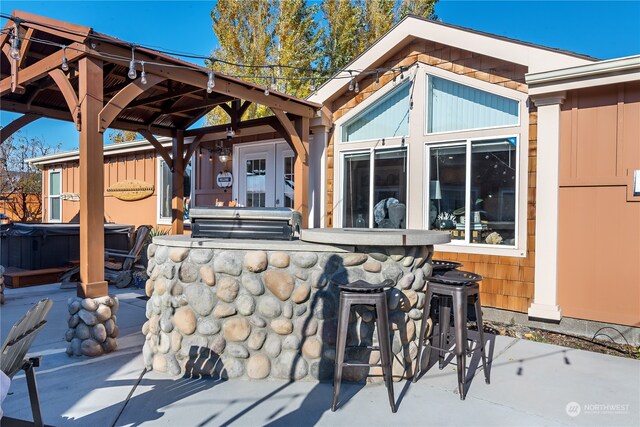 view of patio featuring area for grilling, exterior bar, and a gazebo