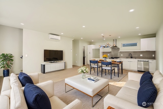 living room featuring a wall mounted AC, light hardwood / wood-style floors, and sink