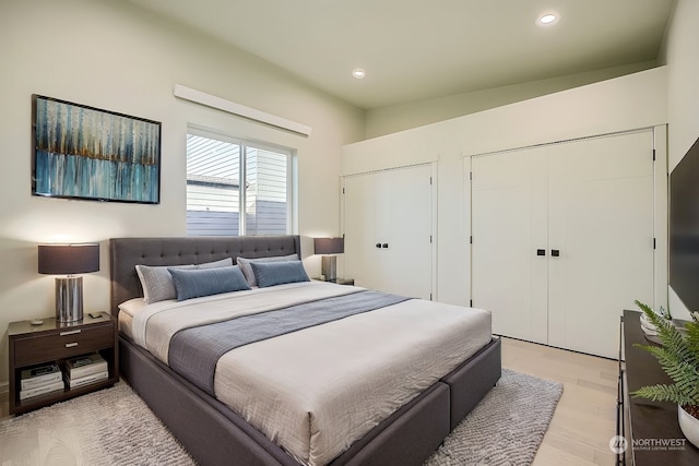 bedroom with light hardwood / wood-style flooring and two closets