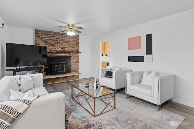 living room with hardwood / wood-style floors, ceiling fan, and a wood stove