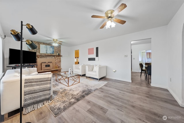 living room featuring hardwood / wood-style flooring, ceiling fan, and a brick fireplace