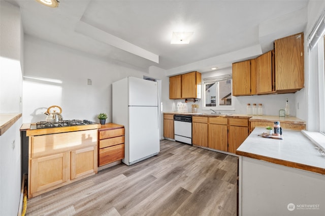 kitchen featuring white appliances, sink, and light wood-type flooring