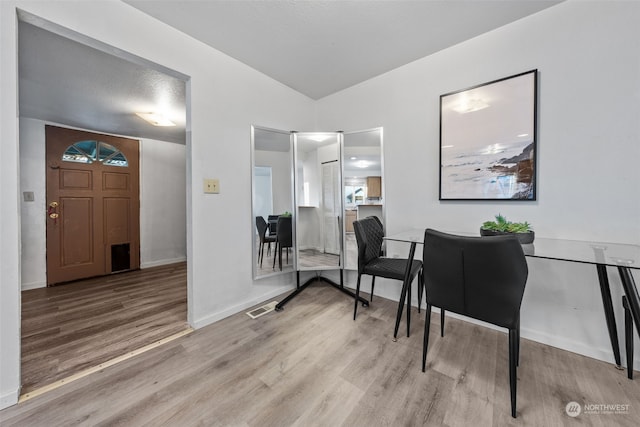 home office featuring light wood-type flooring and vaulted ceiling