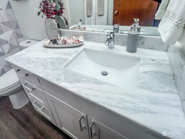 bathroom with hardwood / wood-style floors, vanity, and toilet