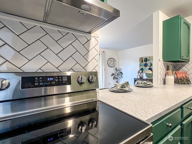 kitchen with stainless steel stove, green cabinetry, exhaust hood, and tasteful backsplash