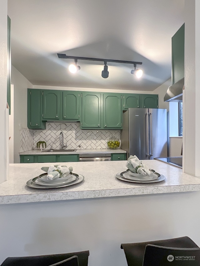 kitchen with green cabinetry, stainless steel appliances, sink, tasteful backsplash, and rail lighting