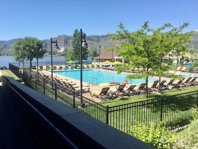 view of swimming pool with a water and mountain view and a patio area