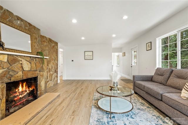 living room featuring a stone fireplace and light hardwood / wood-style flooring