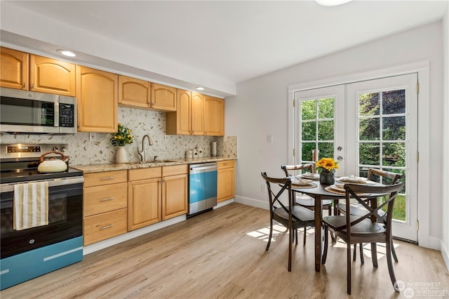 kitchen with light wood-type flooring, appliances with stainless steel finishes, sink, and plenty of natural light