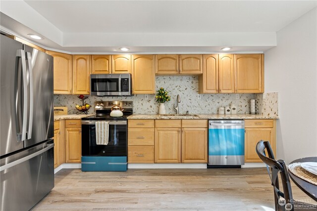 kitchen featuring stainless steel appliances, sink, tasteful backsplash, and light hardwood / wood-style flooring