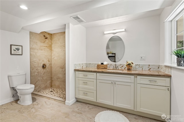 bathroom with vanity, toilet, and tiled shower