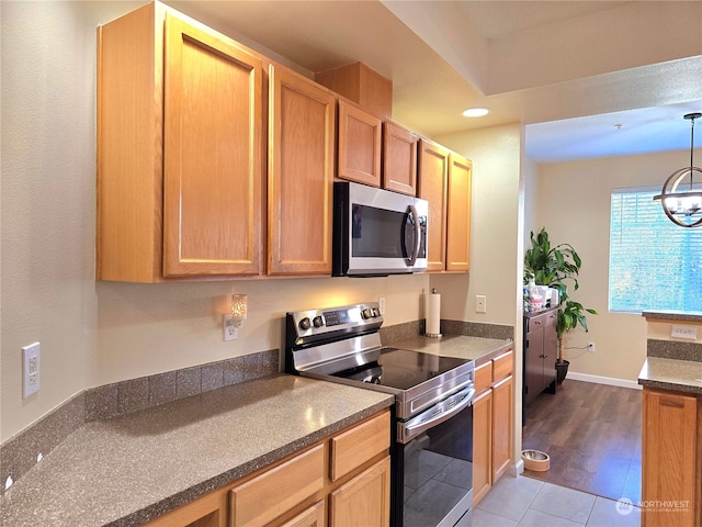 kitchen with hardwood / wood-style flooring, decorative light fixtures, a notable chandelier, and appliances with stainless steel finishes