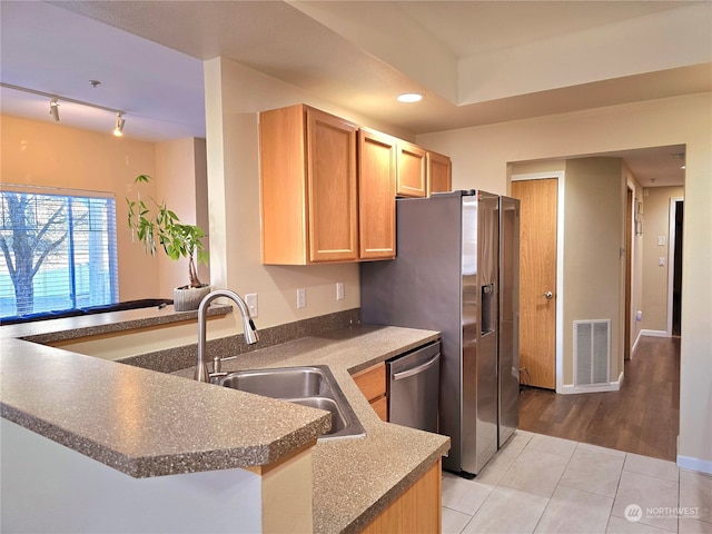 kitchen with kitchen peninsula, appliances with stainless steel finishes, track lighting, sink, and light tile patterned flooring