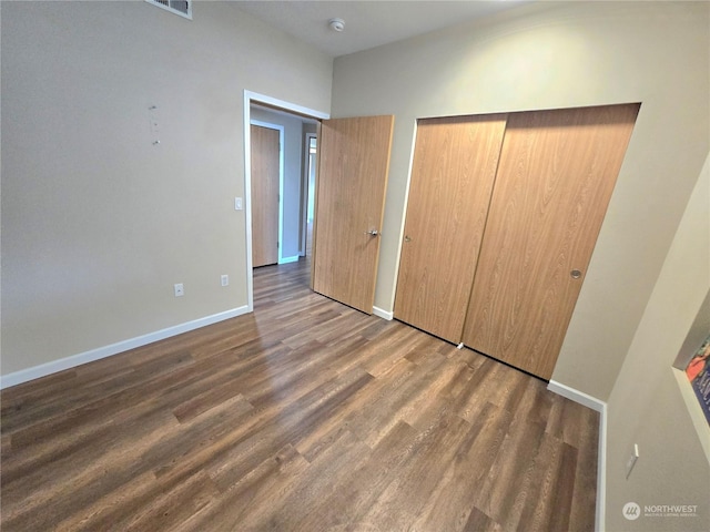 unfurnished bedroom featuring dark wood-type flooring and a closet