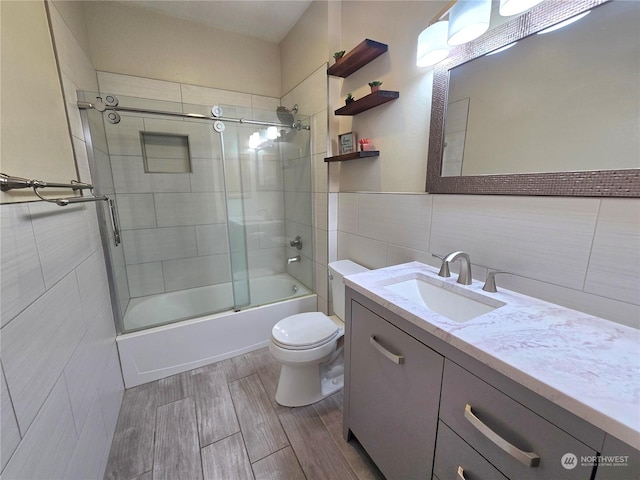 full bathroom with vanity, enclosed tub / shower combo, tile walls, and toilet