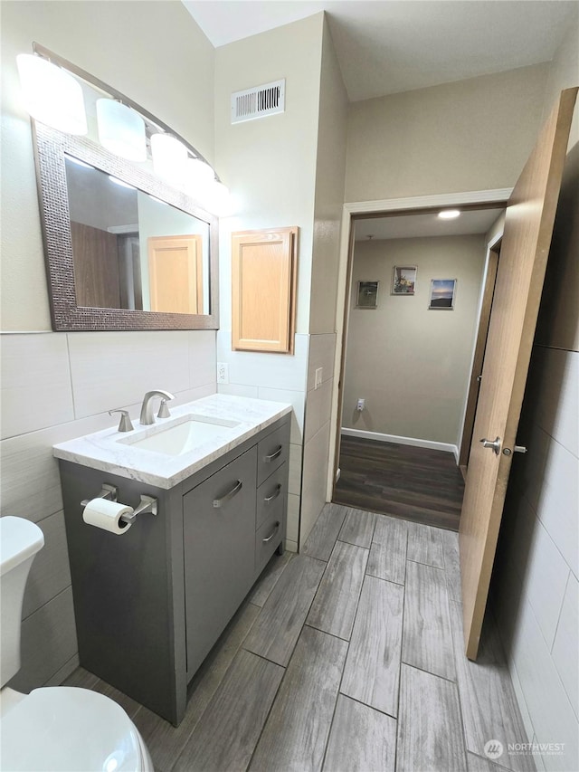 bathroom with vanity, toilet, and tile walls