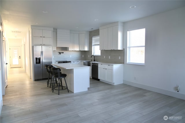 kitchen featuring white cabinetry, stainless steel appliances, a breakfast bar, and a kitchen island