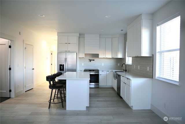 kitchen featuring stainless steel appliances, a kitchen island, white cabinets, and a kitchen breakfast bar