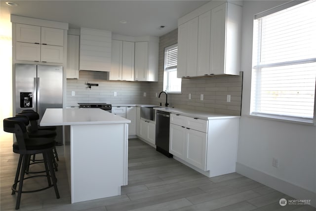 kitchen featuring white cabinetry, sink, a center island, and a breakfast bar