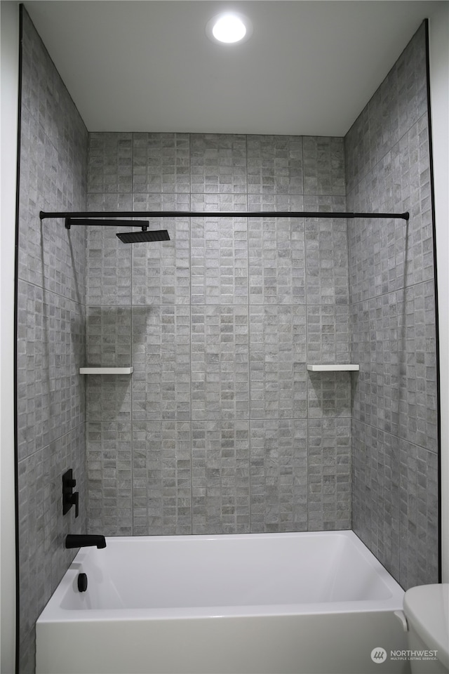 bathroom featuring tiled shower / bath combo and toilet