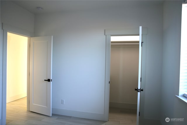 unfurnished bedroom featuring a walk in closet, light wood-type flooring, and a closet