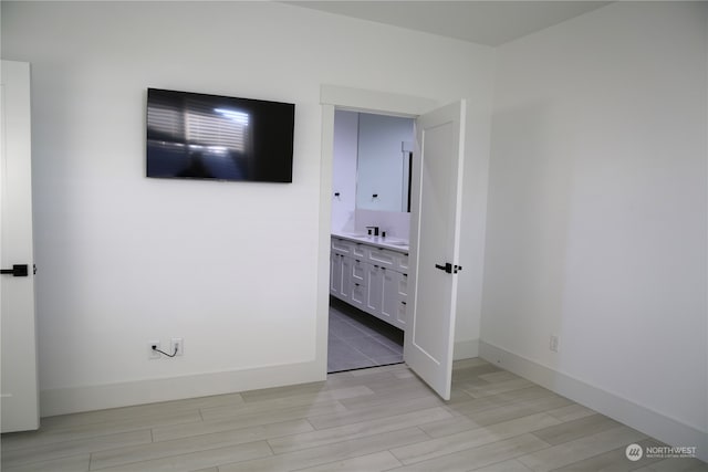 unfurnished bedroom with light hardwood / wood-style flooring and ensuite bathroom