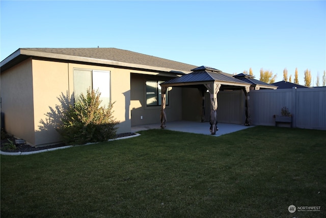 rear view of property featuring a yard, a gazebo, and a patio