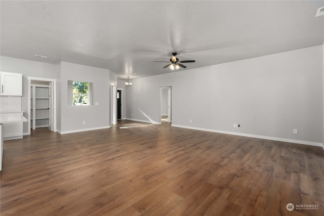 unfurnished living room with a textured ceiling, dark hardwood / wood-style floors, and ceiling fan with notable chandelier