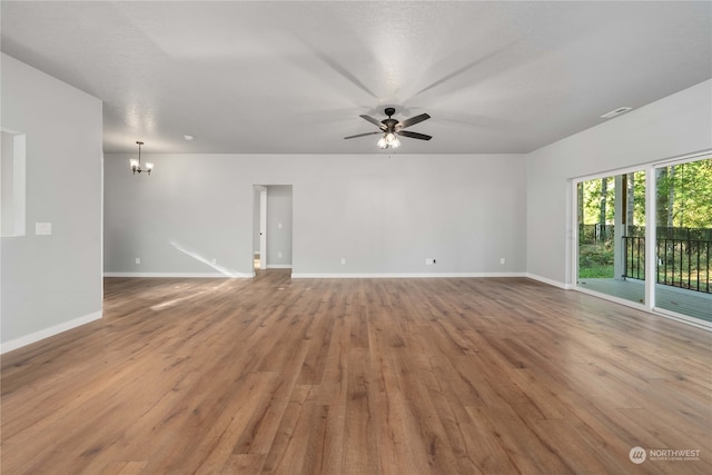 empty room with light hardwood / wood-style floors and ceiling fan with notable chandelier