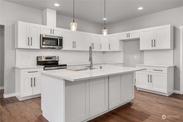 kitchen with dark hardwood / wood-style flooring, white cabinetry, decorative light fixtures, and stainless steel appliances