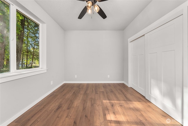 unfurnished bedroom featuring hardwood / wood-style flooring, ceiling fan, and a closet