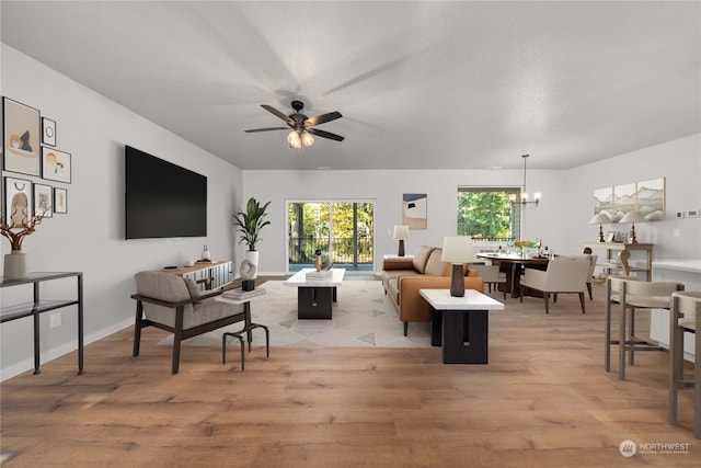 living room with ceiling fan with notable chandelier and light hardwood / wood-style flooring