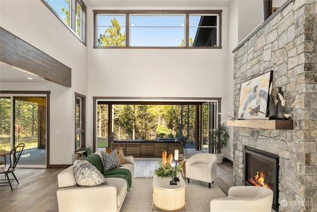 living room featuring a stone fireplace, a wealth of natural light, and a towering ceiling