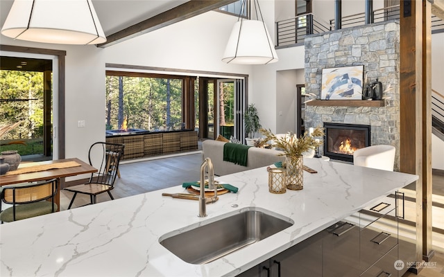 kitchen featuring light stone counters, a stone fireplace, a healthy amount of sunlight, and sink