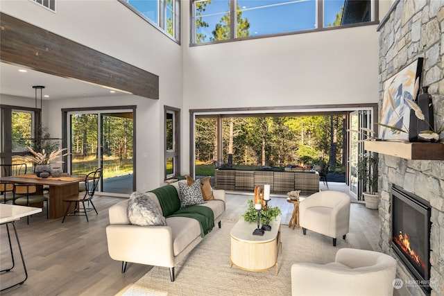 living room with a fireplace, wood-type flooring, and a towering ceiling