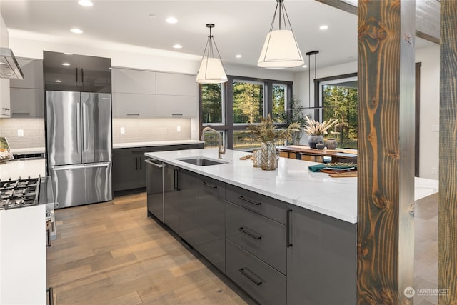 kitchen featuring gray cabinetry, sink, stainless steel appliances, pendant lighting, and light wood-type flooring