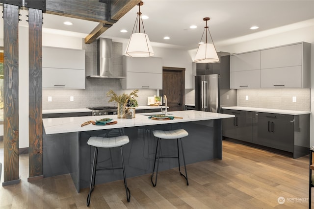 kitchen featuring gray cabinetry, wall chimney exhaust hood, appliances with stainless steel finishes, and light hardwood / wood-style flooring