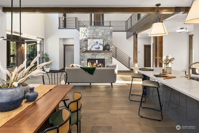 living room featuring dark hardwood / wood-style floors, a stone fireplace, a towering ceiling, and sink