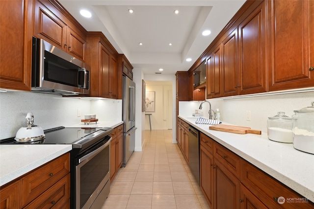 kitchen featuring stainless steel appliances, light tile patterned floors, light stone counters, and sink