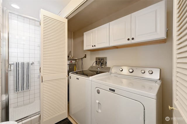 washroom featuring cabinets and washer and clothes dryer