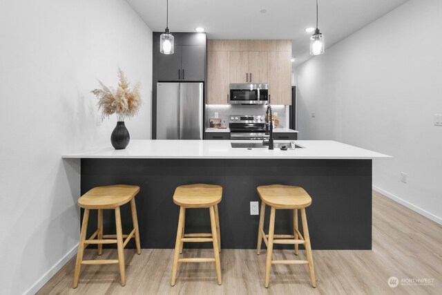 kitchen featuring a kitchen breakfast bar, pendant lighting, and stainless steel appliances