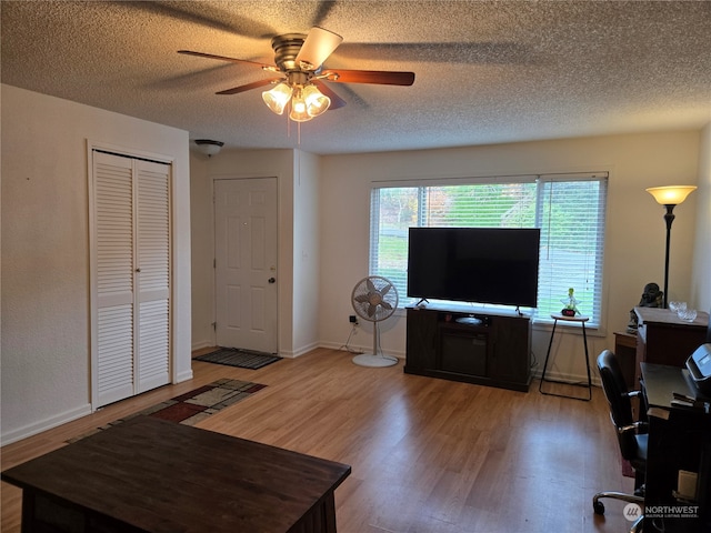 living room with a textured ceiling, hardwood / wood-style flooring, and ceiling fan