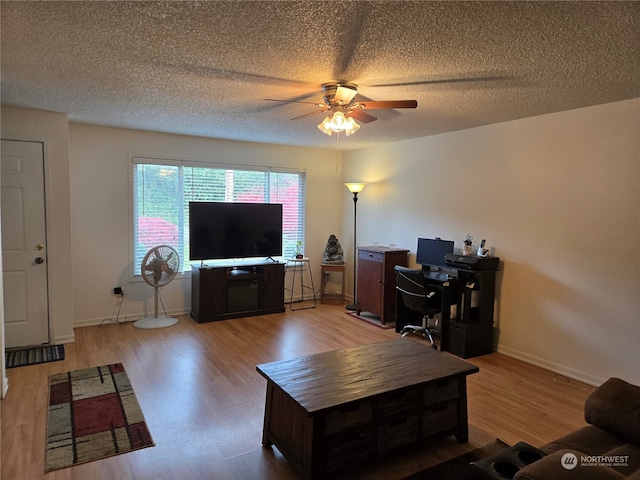 living room with ceiling fan, wood-type flooring, and a textured ceiling