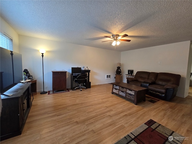 living room featuring ceiling fan, a textured ceiling, and light wood-type flooring