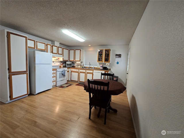 kitchen featuring light wood-type flooring, a textured ceiling, exhaust hood, sink, and white appliances