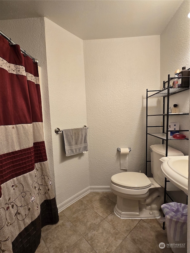 bathroom featuring a shower with shower curtain, tile patterned floors, and toilet